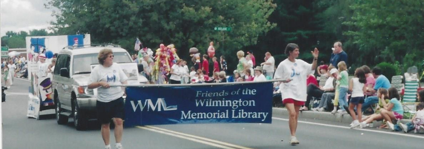 Two members of The Friends of the Wilmington Memorial Library with their banner between them marching in a parade.