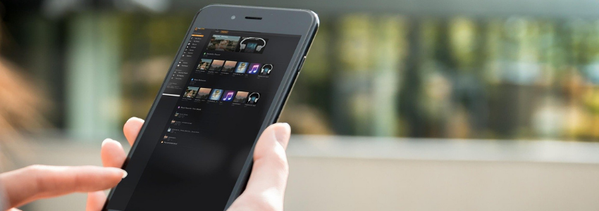 A smart phone with a list of apps on the screen in a hand with a finger ready to tap the screen.