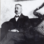 Ed Nelson Eames sitting on a couch with the bottom of a picture above him